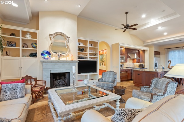 living room with arched walkways, lofted ceiling, recessed lighting, a premium fireplace, and a ceiling fan