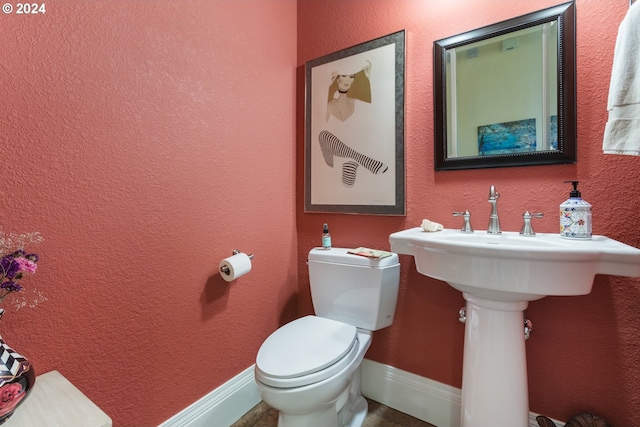 bathroom with baseboards, a textured wall, and toilet