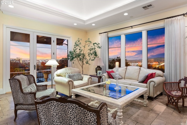 living area featuring ornamental molding, stone tile flooring, visible vents, and a raised ceiling