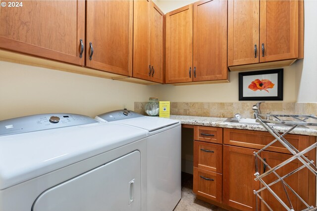 clothes washing area with cabinets, sink, and washing machine and clothes dryer