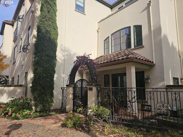 exterior space with a fenced front yard, a gate, a tiled roof, and stucco siding