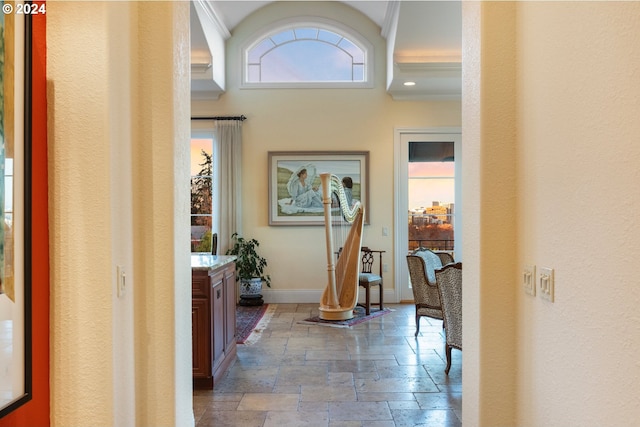 corridor featuring baseboards, plenty of natural light, and stone tile floors