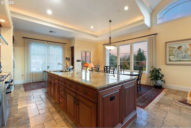 kitchen with pendant lighting, a raised ceiling, a center island with sink, and stone tile floors