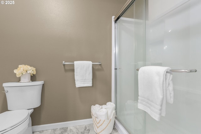 bathroom with baseboards, a shower stall, toilet, and marble finish floor