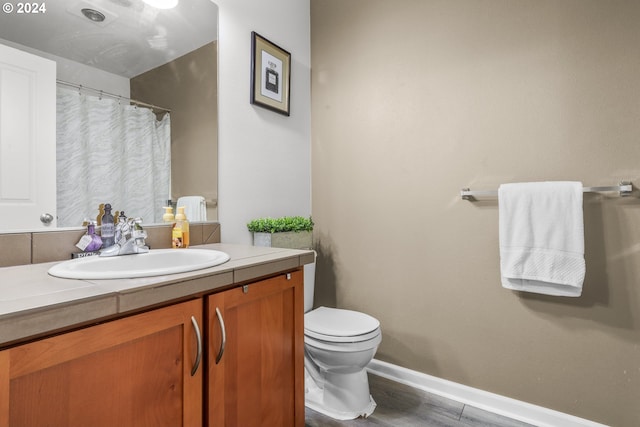 full bath with a shower with curtain, vanity, toilet, baseboards, and wood finished floors