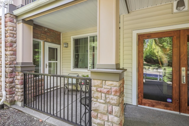 view of exterior entry featuring a porch and stone siding