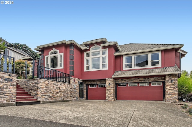 view of front of house featuring a tile roof, stucco siding, concrete driveway, a garage, and stone siding