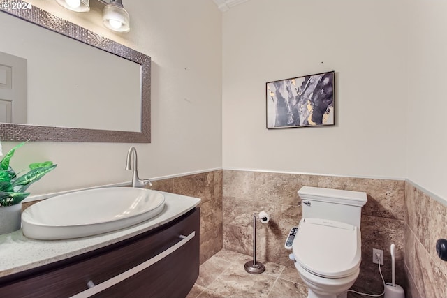 bathroom featuring toilet, wainscoting, tile walls, and vanity