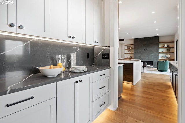 kitchen with decorative backsplash, white cabinets, and light wood-type flooring