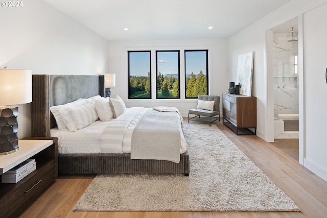 bedroom featuring connected bathroom and light hardwood / wood-style flooring