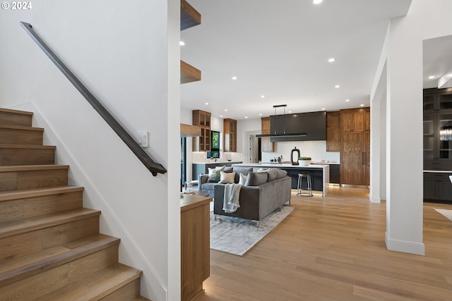living area featuring light wood-type flooring, stairs, and recessed lighting