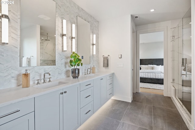 ensuite bathroom with double vanity, a stall shower, decorative backsplash, ensuite bath, and a sink