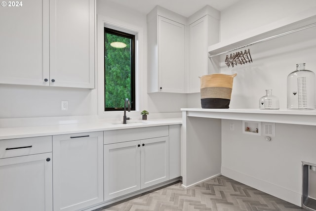 clothes washing area with washer hookup, a sink, cabinet space, and baseboards