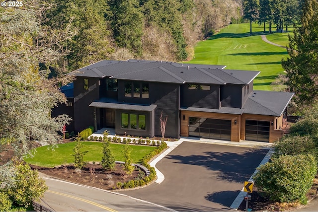 view of front of house featuring an attached garage, aphalt driveway, and a front yard
