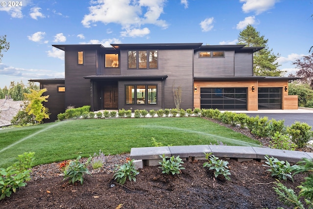 modern home featuring a garage, driveway, and a front lawn