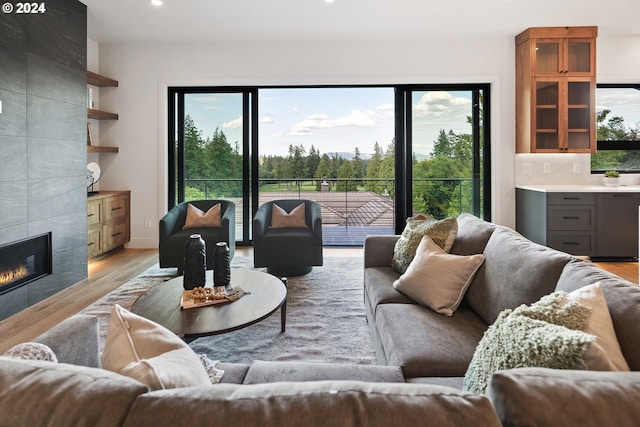 living room featuring light wood-style floors, a wealth of natural light, a tiled fireplace, and recessed lighting