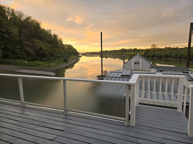 deck at dusk featuring a water view