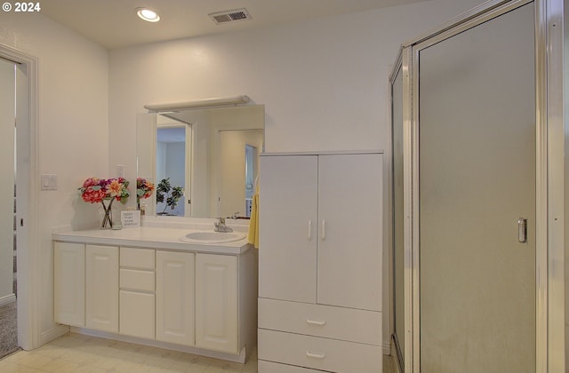 bathroom featuring a shower with door and vanity