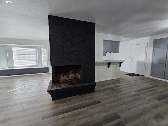 living room featuring a fireplace, wood finished floors, baseboards, and a textured ceiling