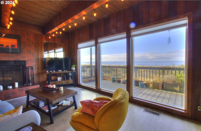 living room featuring beamed ceiling, hardwood / wood-style floors, wooden ceiling, and a tiled fireplace