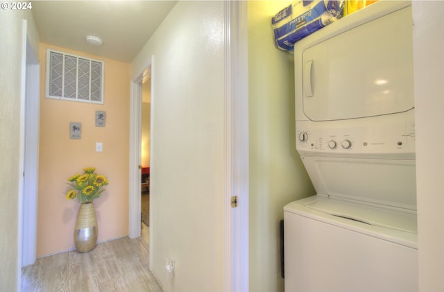 clothes washing area featuring stacked washer / dryer and light hardwood / wood-style flooring