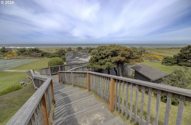 wooden terrace featuring a water view and a lawn