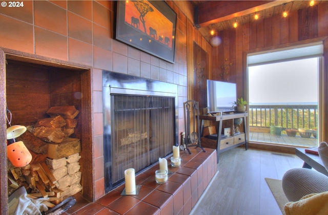 living room with beam ceiling, a tile fireplace, and dark hardwood / wood-style floors