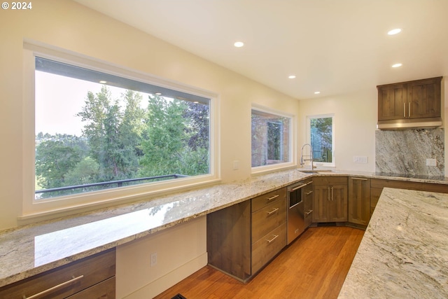 kitchen featuring sink, light wood-type flooring, decorative backsplash, and light stone counters