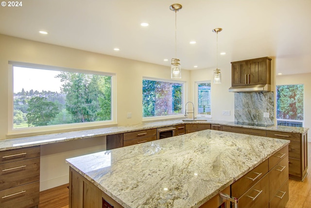 kitchen with sink, pendant lighting, black electric stovetop, and light stone counters