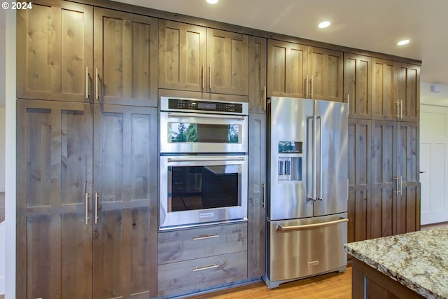 kitchen featuring stainless steel appliances, light stone counters, and light hardwood / wood-style flooring