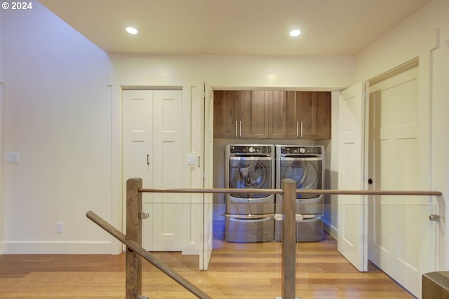 laundry area with cabinets, washer and clothes dryer, and light hardwood / wood-style flooring