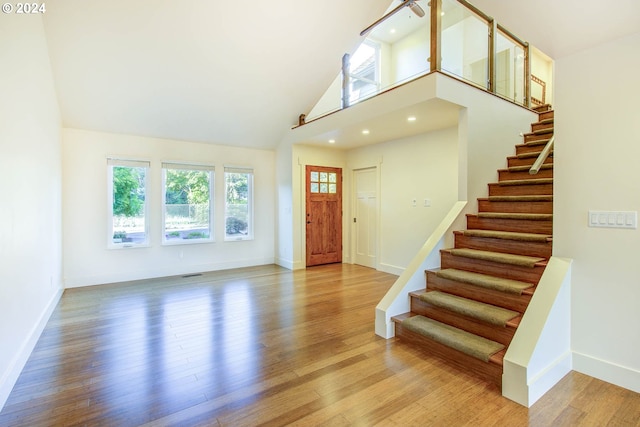 entryway featuring light wood-type flooring, a towering ceiling, and plenty of natural light