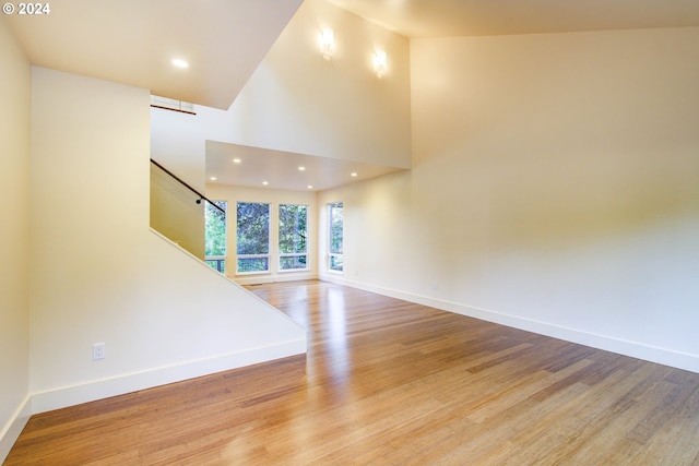 unfurnished living room with a towering ceiling and light wood-type flooring