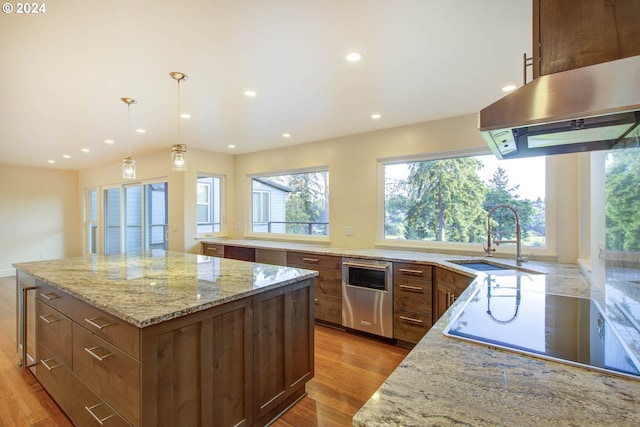 kitchen with light stone countertops, sink, decorative light fixtures, and a center island