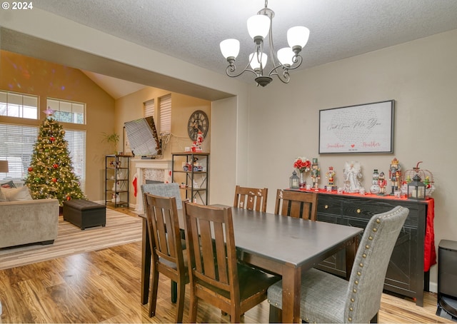 dining area featuring lofted ceiling, light wood-type flooring, a textured ceiling, and a chandelier