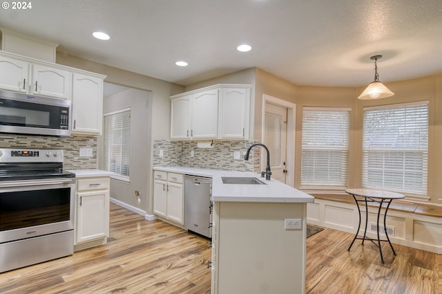 kitchen with sink, hanging light fixtures, light hardwood / wood-style flooring, white cabinets, and appliances with stainless steel finishes