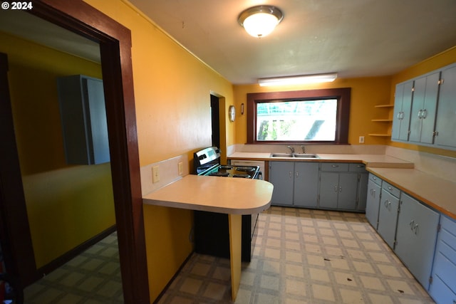 kitchen featuring a kitchen bar, kitchen peninsula, stainless steel range, and sink