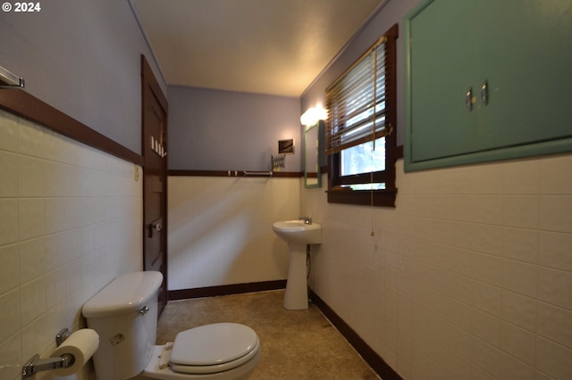 bathroom featuring toilet, tile walls, and sink