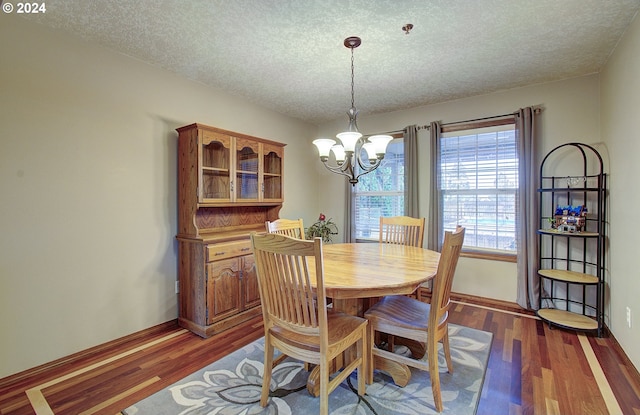 dining room featuring an inviting chandelier, a textured ceiling, and dark hardwood / wood-style floors