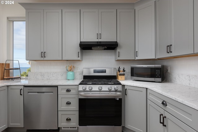 kitchen featuring exhaust hood, gray cabinets, and appliances with stainless steel finishes