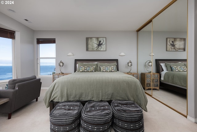 carpeted bedroom with a closet and a water view