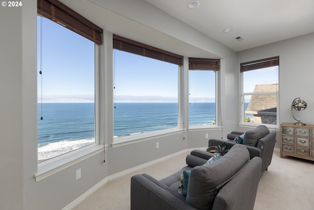 living room featuring light colored carpet, a beach view, and a water view