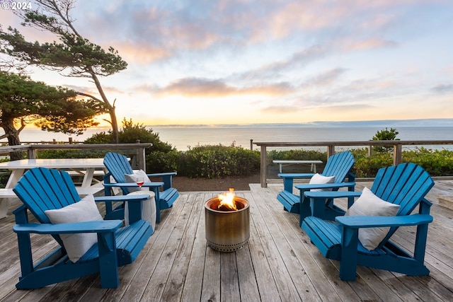 deck at dusk featuring a fire pit and a water view