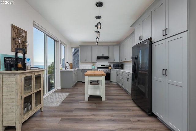 kitchen featuring tasteful backsplash, wooden counters, gray cabinets, a kitchen island, and appliances with stainless steel finishes