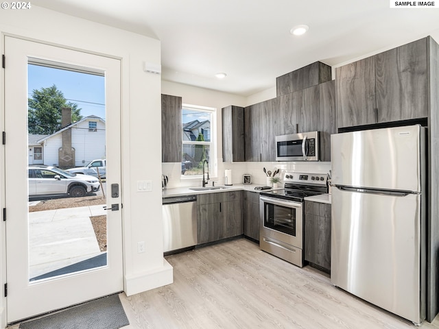 kitchen featuring sink, appliances with stainless steel finishes, tasteful backsplash, dark brown cabinets, and light hardwood / wood-style floors