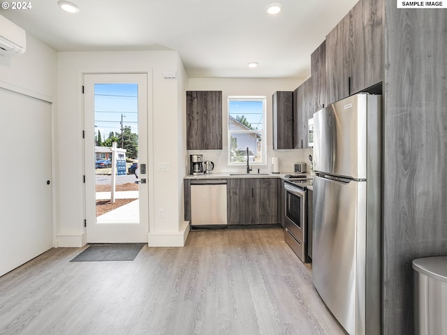 kitchen featuring sink, stainless steel appliances, light hardwood / wood-style flooring, a wall unit AC, and dark brown cabinets