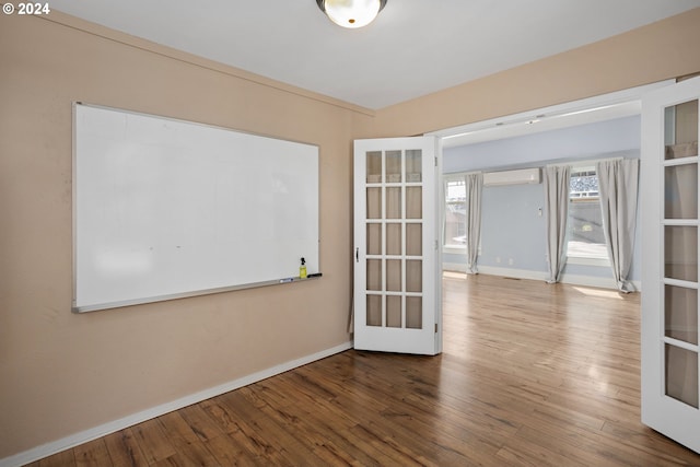 spare room with hardwood / wood-style flooring, french doors, and a wall mounted AC