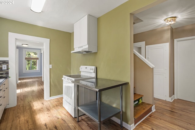 kitchen with white cabinets, light hardwood / wood-style flooring, and electric range