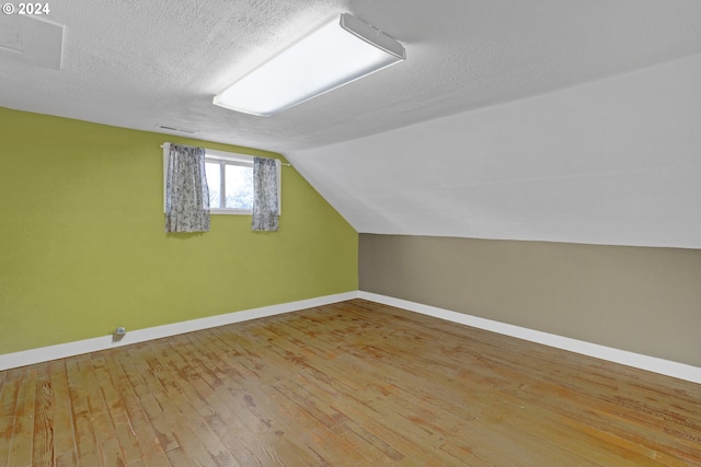 bonus room with vaulted ceiling, a textured ceiling, and hardwood / wood-style flooring