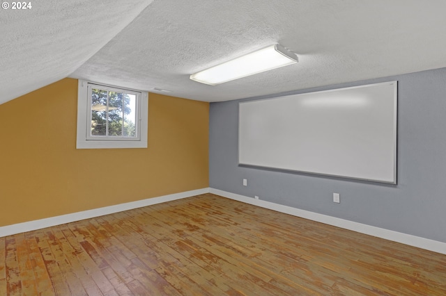 interior space featuring a textured ceiling, light hardwood / wood-style floors, and vaulted ceiling